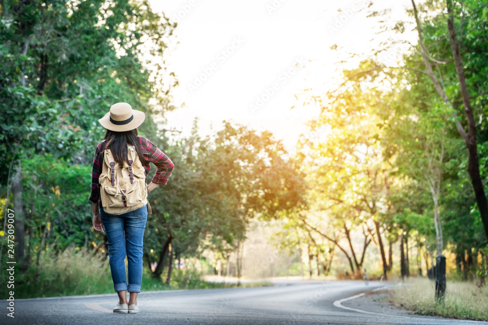 Asian woman backpack on the road and forest background, journey and traveling on holiday concept .