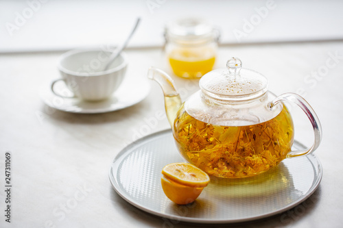 lime tea in a transparent teapot, lemon and honey. Yellow and white