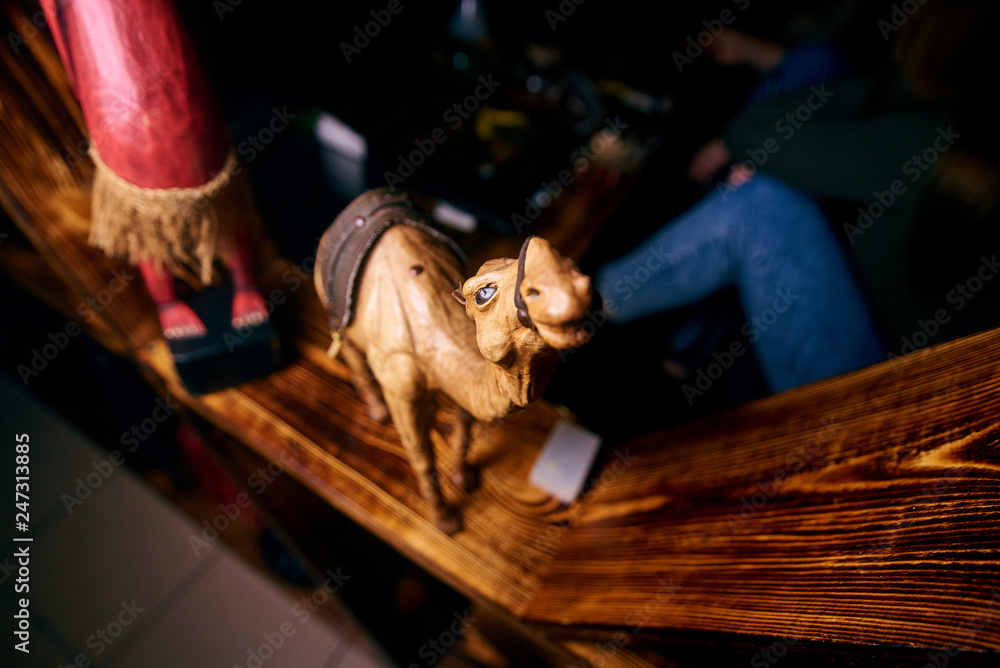 a yellow camel figurine stands on a wooden shelf a yellow camel figurine stands on a wooden shelf