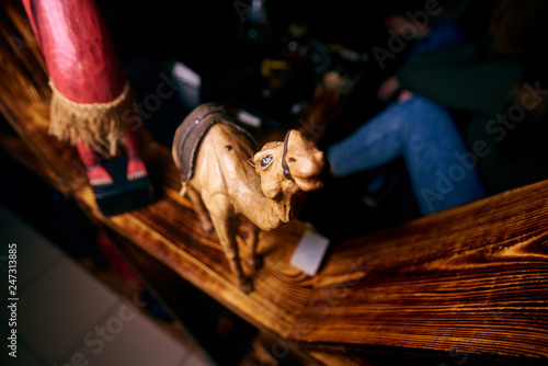 a yellow camel figurine stands on a wooden shelf © Светлана Наклейщиков