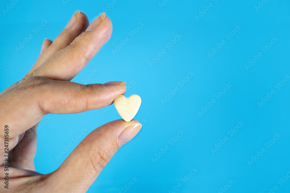 Medical background with multi-colored packs of pills. Сoncept pharmacy, clinic, drugs, headache medicine. Image on illness, flu, treatment. Hand holding a pill in the shape of a heart