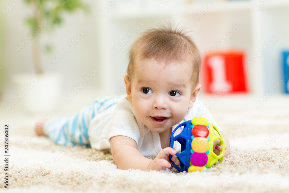 Adorable baby having fun with toy on cozy rug. Happy cheerful kid boy playing on the floor Adorable baby having fun with toy on cozy rug. Happy cheerful kid boy playing on the floor