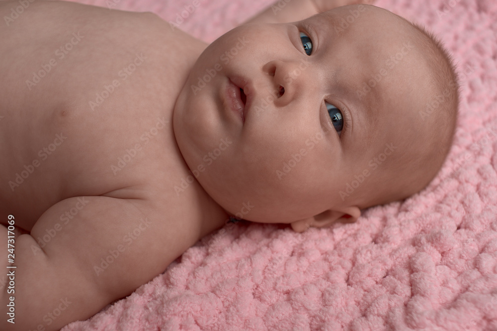 baby with a surprised face with open mouth. The baby lies on a pink micro-polyester rug. baby with a surprised face with open mouth. The baby lies on a pink micro-polyester rug.