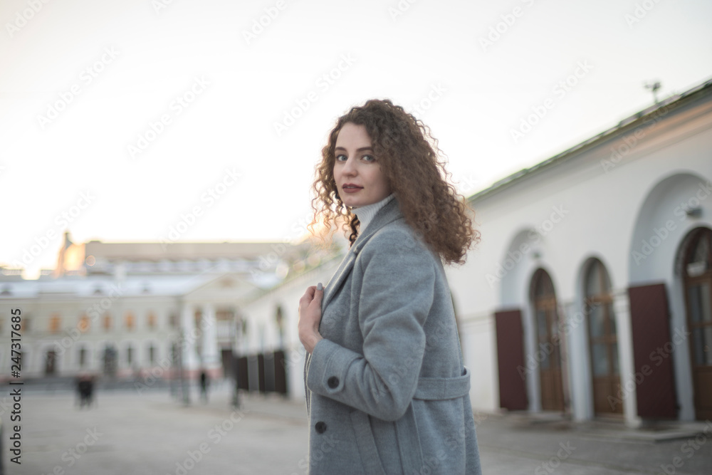 girl in a coat walks around the city