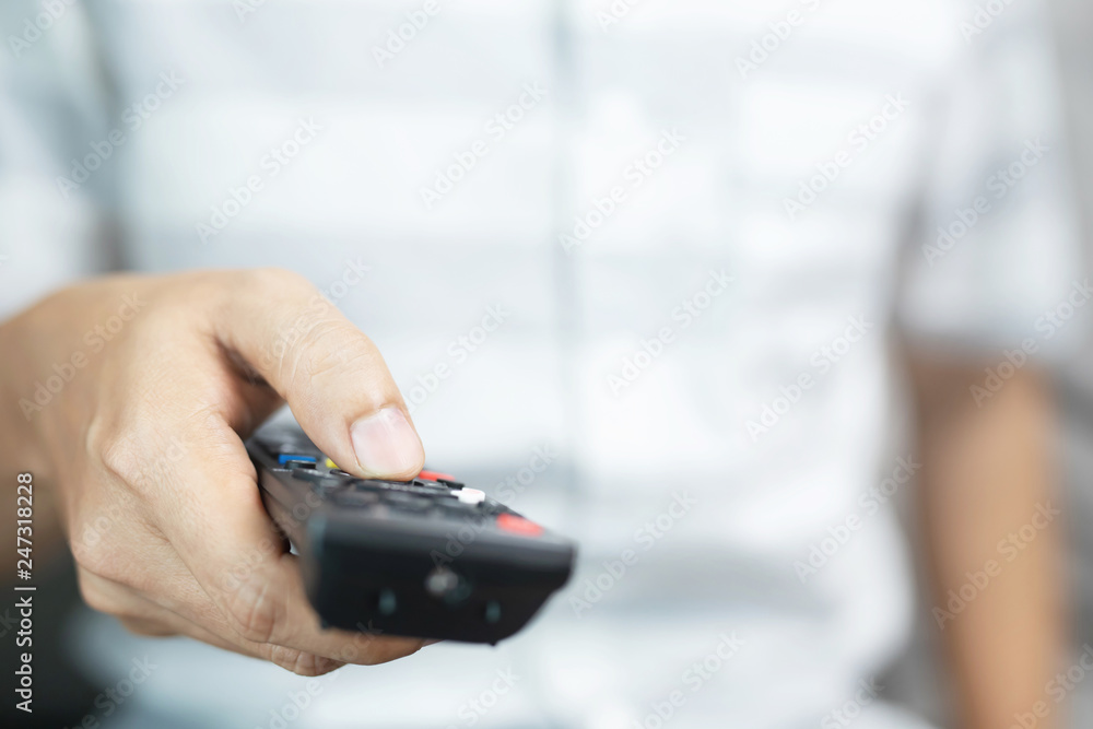 Close up young man using television remote control is sitting on a sofa. on or off tv. Close up young man using television remote control is sitting on a sofa. on or off tv.
