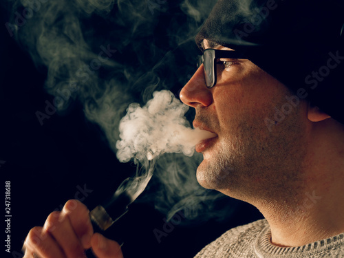smoking man in e-cigarette smoke on black background