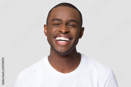 Cheerful happy african millennial man laughing looking at camera isolated on studio blank background, funny young black guy with healthy teeth beaming orthodontic white wide smile head shot portrait