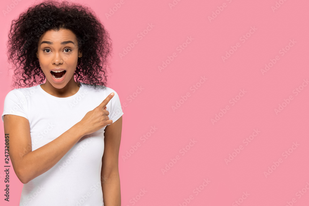 Amazed african woman pointing finger at copyspace surprised by unbelievable sale, excited female customer look at camera indicate blank space advertise cheap offer isolated on pink studio background Amazed african woman pointing finger at copyspace surprised by unbelievable sale, excited female customer look at camera indicate blank space advertise cheap offer isolated on pink studio background