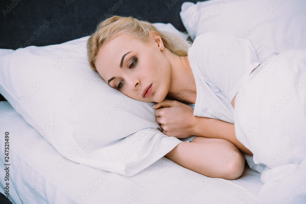 beautiful sad woman holding blanket while lying in bed at home beautiful sad woman holding blanket while lying in bed at home