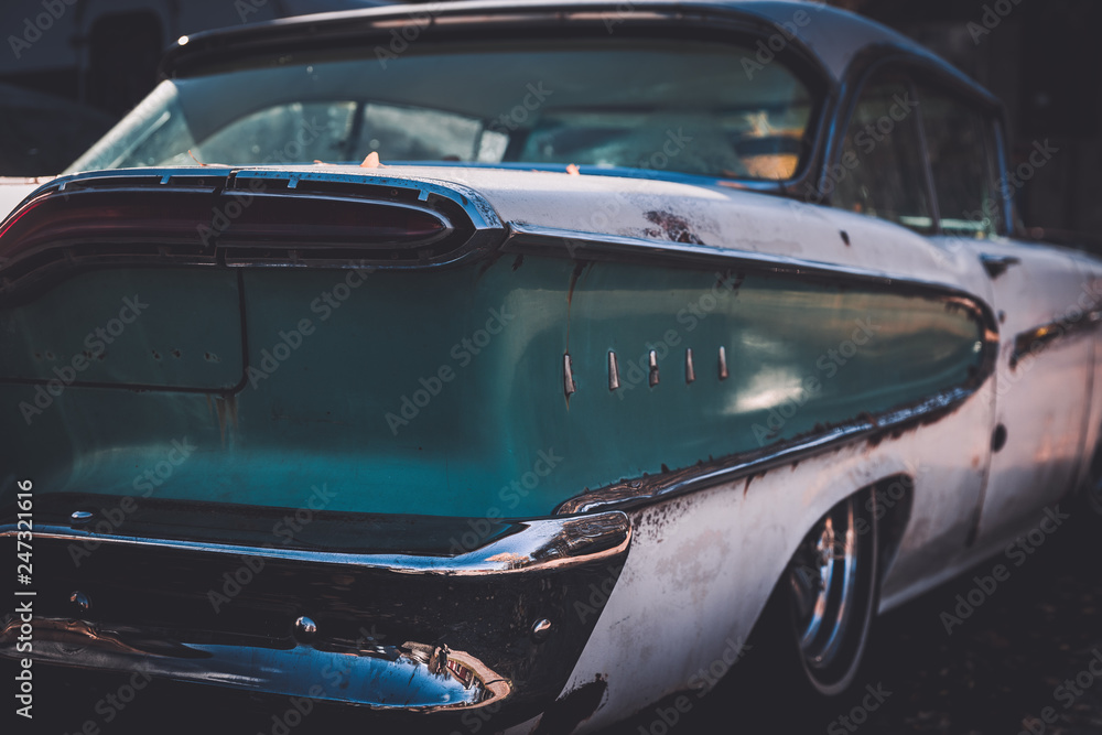 Rear end of a worn and beat up classic American car from the fifties