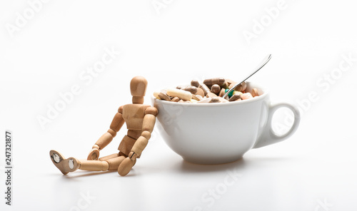 Vitamin cocktail. Health problem. Immunity care and medicine vitamins. Fast treatment. Mixing medicines. Take medicine concept. Medicines dose. Wooden human dummy near cup full pills and tablets