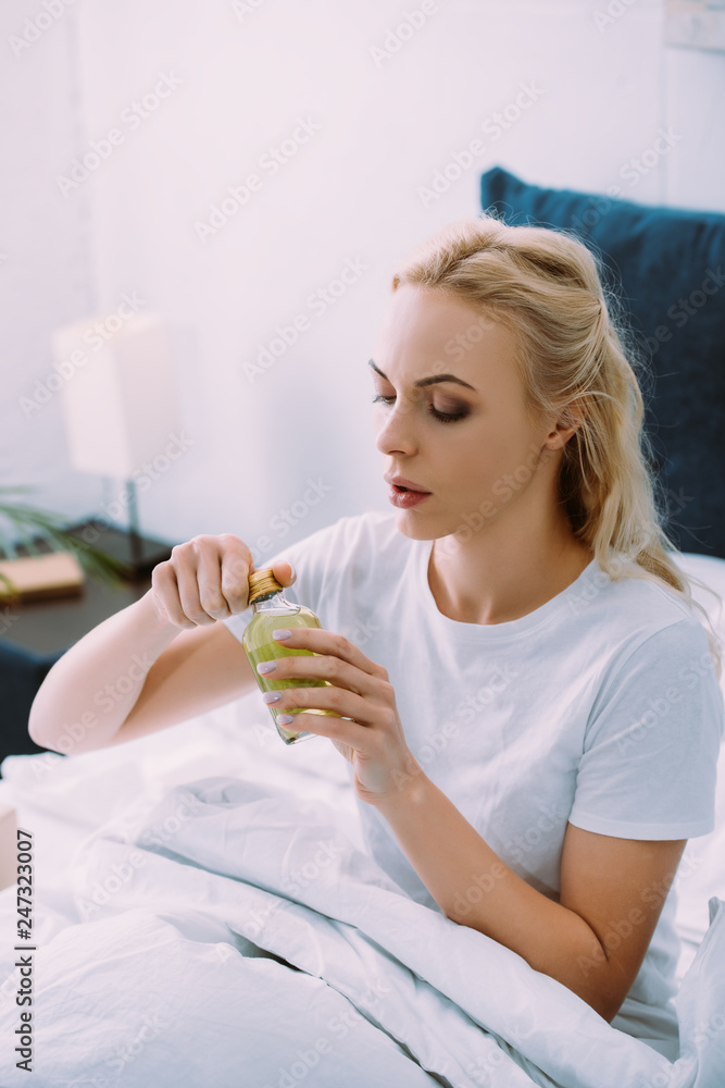 upset woman holding bottle with medicine in bed upset woman holding bottle with medicine in bed