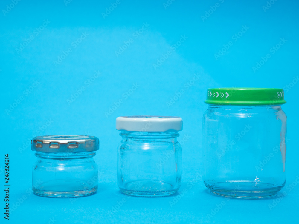 closeup of three glass jars on blue background. different sizes and unlabeled closeup of three glass jars on blue background. different sizes and unlabeled