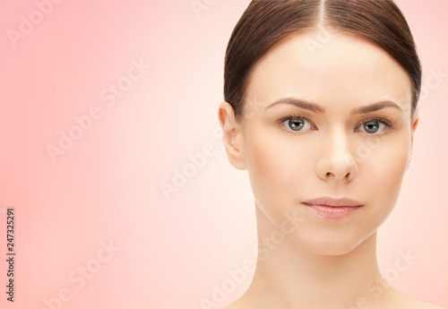 beauty and people concept - face of beautiful young woman over pink background