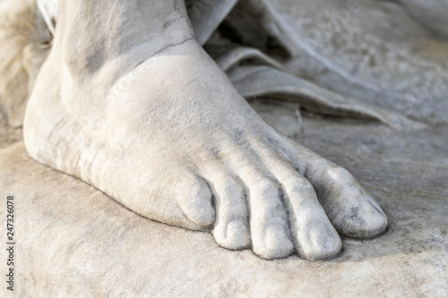 Part of leg of ancient marble statue. Close-up stone foot. Pedicure and feet care concept