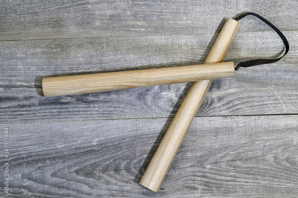 Nunchucks on vintage wooden background. The concept of invitation to training.