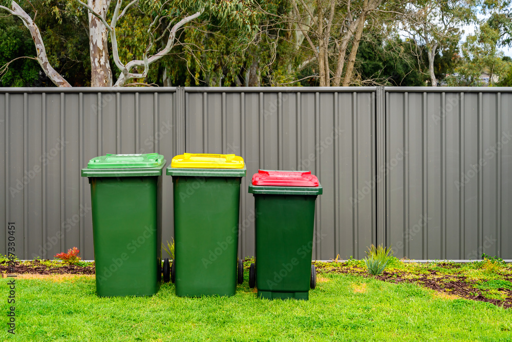 Australian home wheelie bins set provided by local council on back yard Australian home wheelie bins set provided by local council on back yard