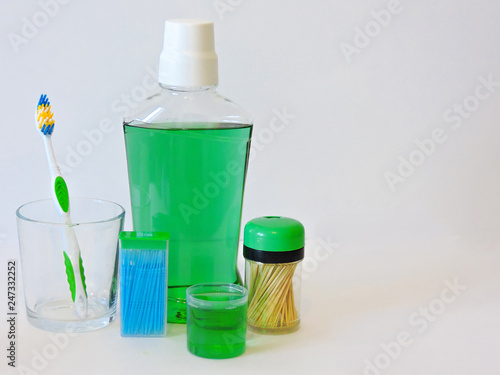 Bottle and glass of mouthwash on bath shelf with toothbrush. Dental oral hygiene concept. Set of oral care products.Flat lay composition with manual toothbrushes and oral hygiene products. 