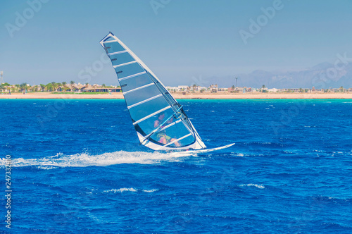 a windsurfer on a board under a praus at a speed moves along the surface of the sea