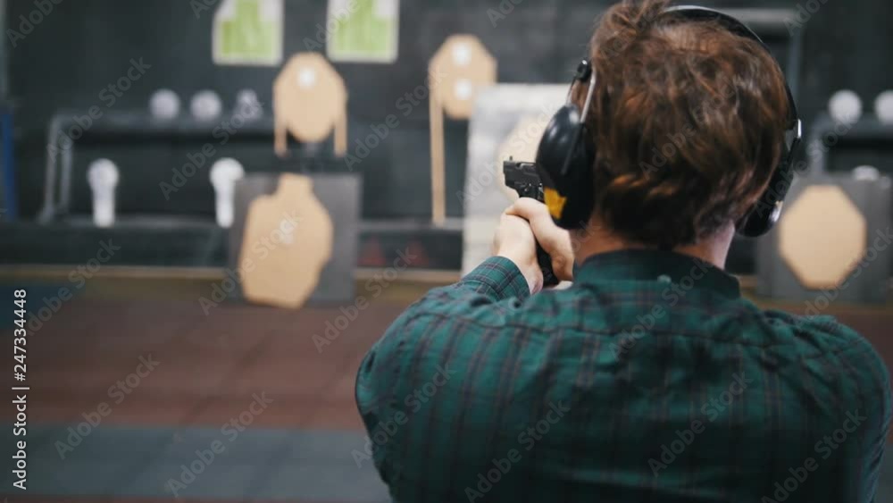 Shooting gallery. A concentrated young man shooting on a shooting range. Shooting gallery. A concentrated young man shooting on a shooting range.