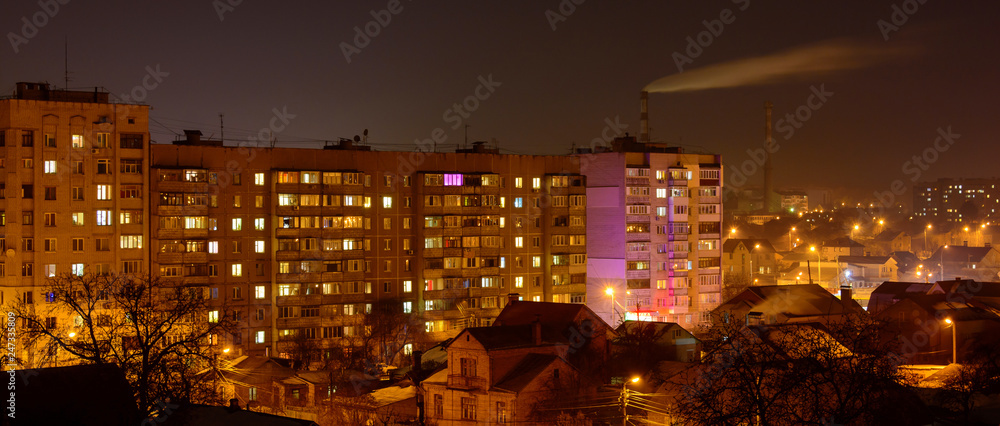 Photo of buildings at night with factory smoke above them