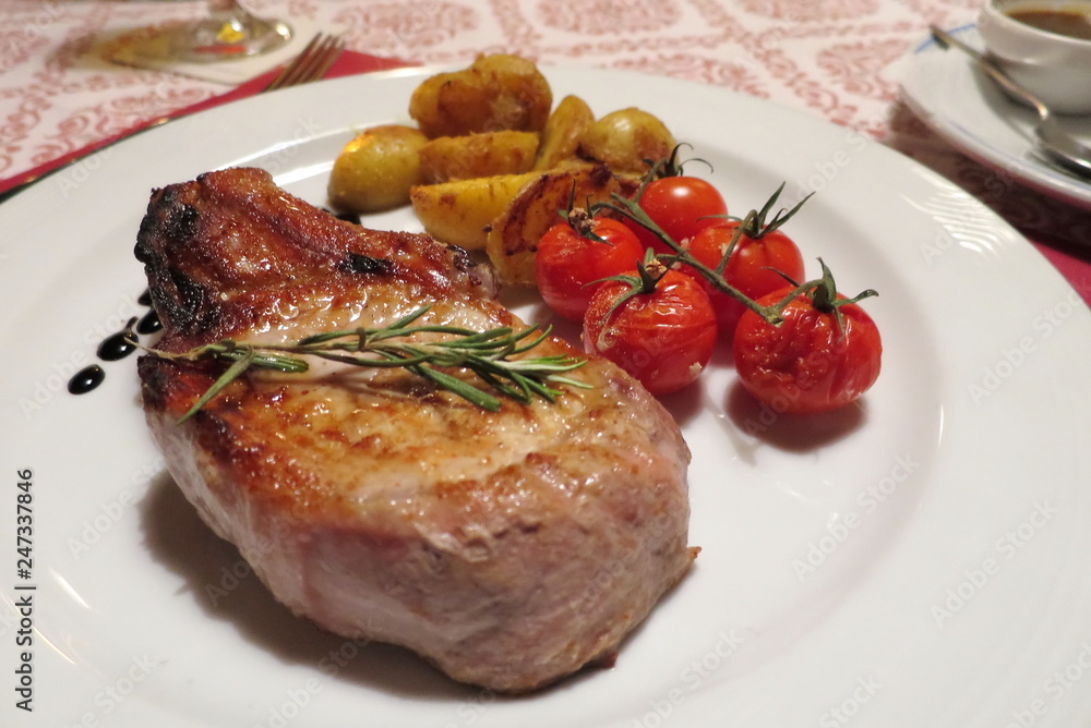Beef or pork steak with tomato and potato grilled on white plate. Food concept. Beef or pork steak with tomato and potato grilled on white plate. Food concept.