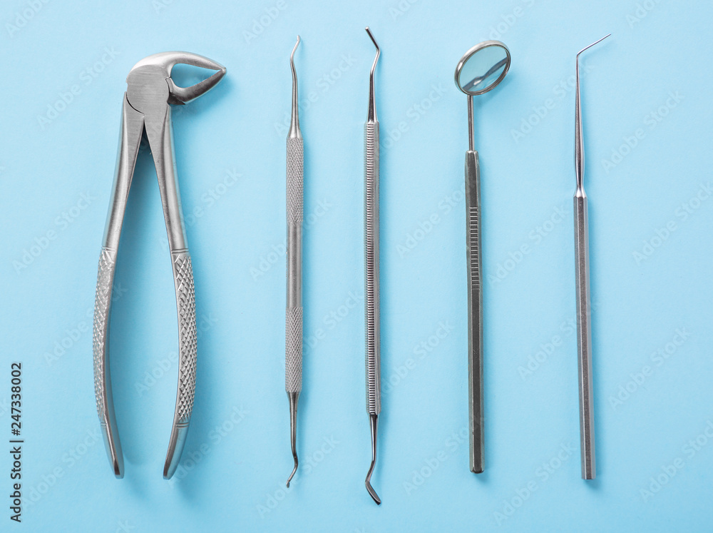Dental health and teethcare concept. Top view of dental tools set on blue background in dentists clinic: dental mirror, explorers, forceps. Dental health and teethcare concept. Top view of dental tools set on blue background in dentists clinic: dental mirror, explorers, forceps.