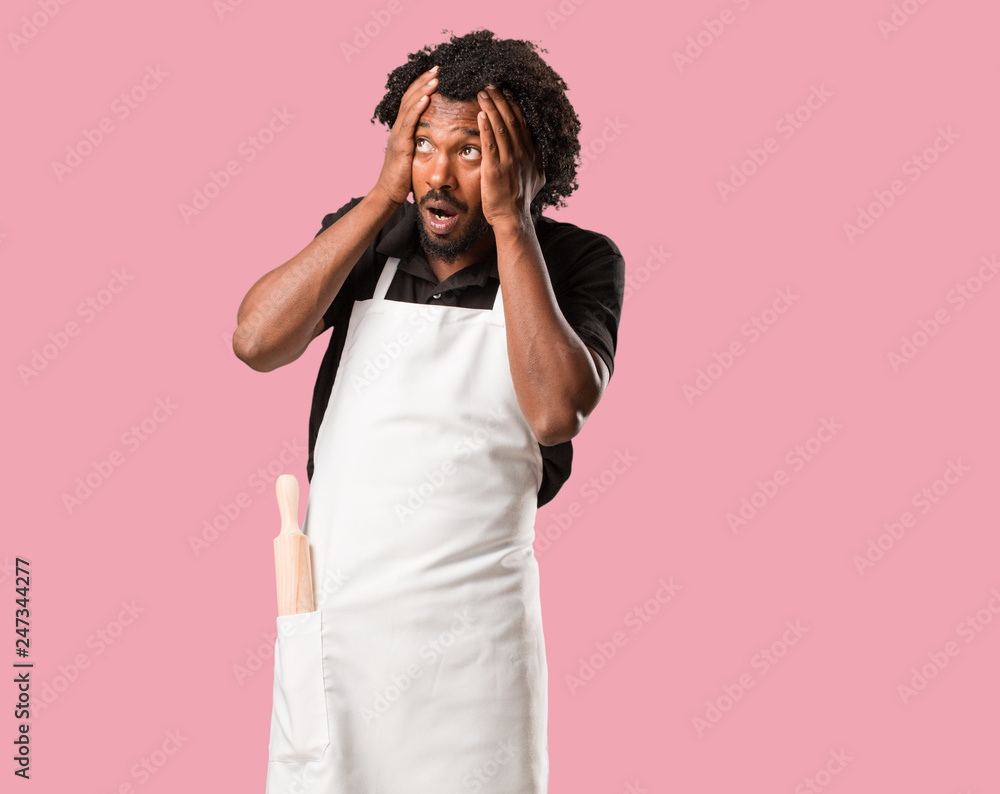 Handsome african american baker frustrated and desperate, angry and sad with hands on head Handsome african american baker frustrated and desperate, angry and sad with hands on head