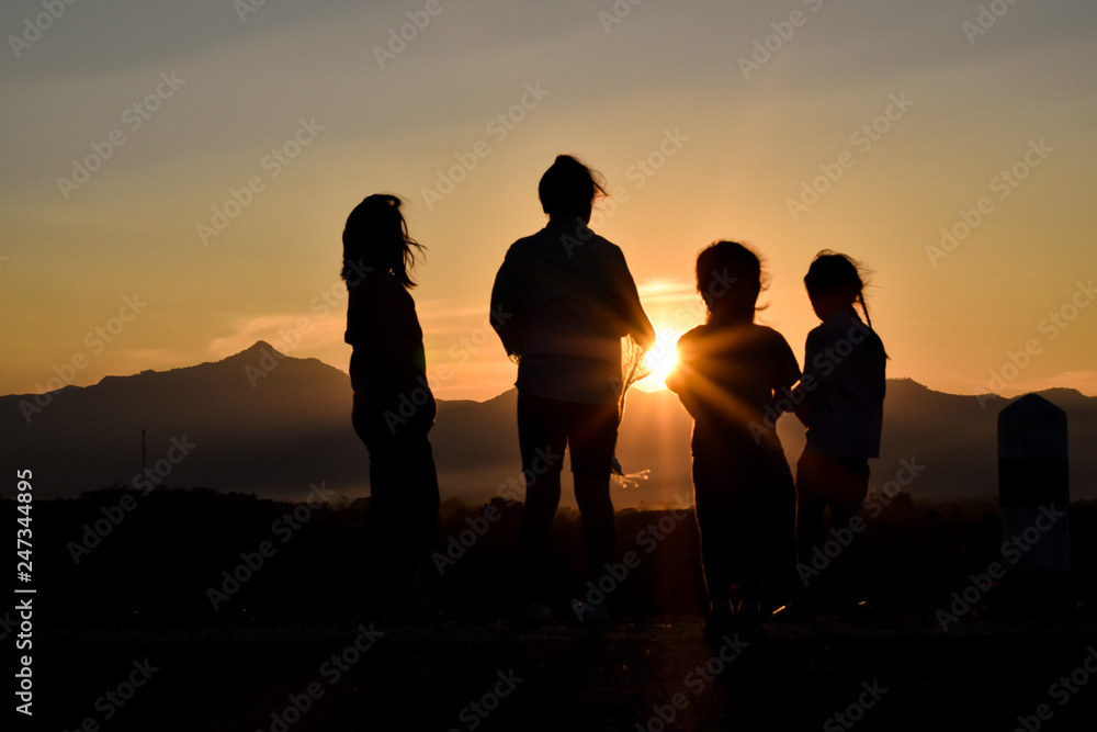 © banphote - Silhouette of a happy family at sunset.