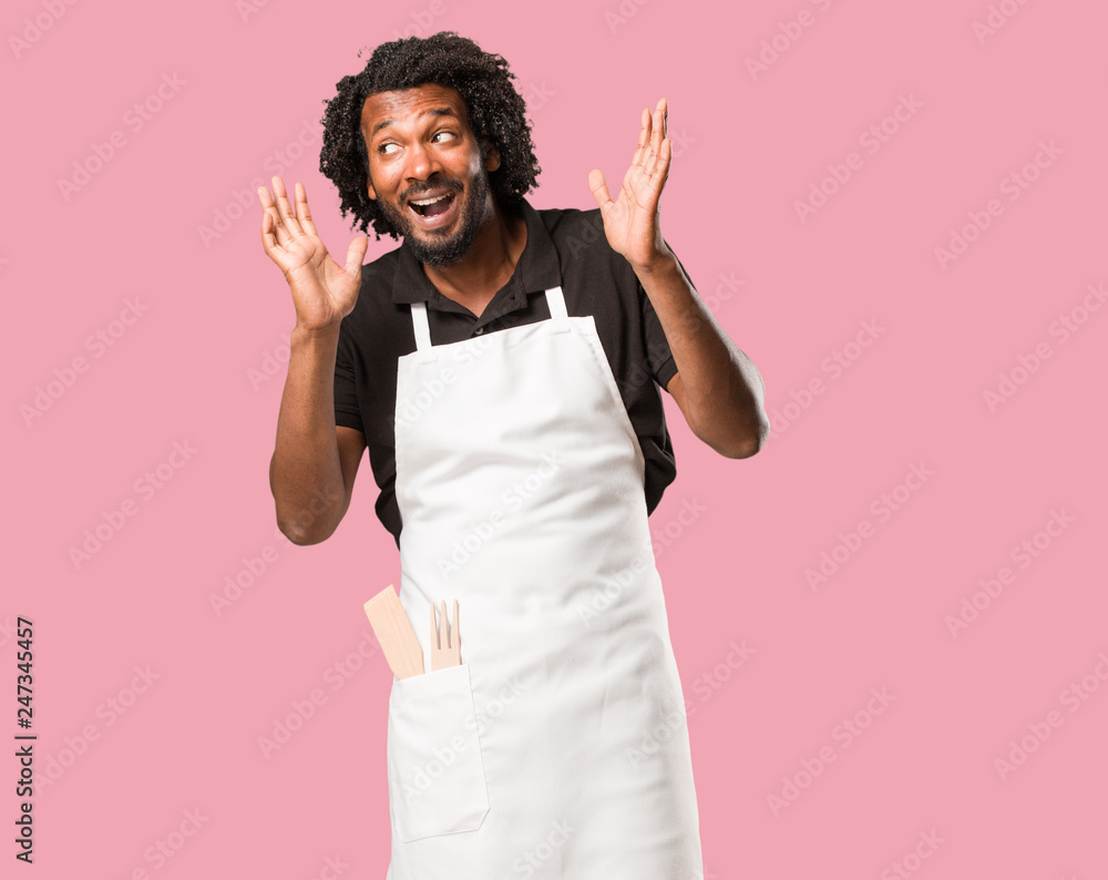 Handsome african american baker surprised and shocked, looking with wide eyes, excited by an offer or by a new job, win concept Handsome african american baker surprised and shocked, looking with wide eyes, excited by an offer or by a new job, win concept