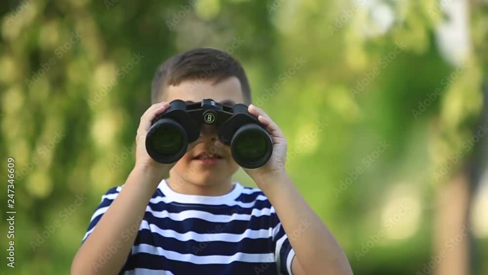 Little boy walking in the park and looking through binoculars Little boy walking in the park and looking through binoculars