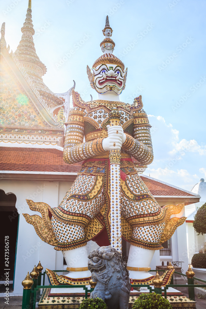 Fototapeta premium ancient temple guardian in front of Temple of Dawn (Wat Arun Buddhist Temple) is white demon giant statue named Sahatsadecha. Thailand Traditional Tourist Attraction, Thai Travel and Tourism concept