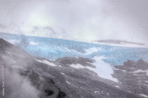 A sneak view through the clouds of the Svartisen glacier seen from the jetty at the Holandsfjord