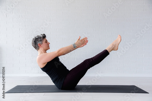 Mature Caucasian woman practicing yoga on livingroom floor. Middle aged woman doing yoga indoors. photo