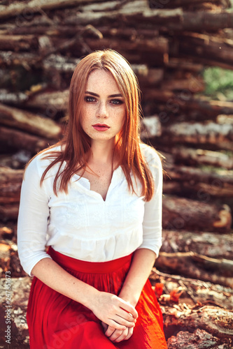 Portrait of young tender redhead young girl with healthy freckled skin wearing white top looking at camera with serious or pensive expression. Caucasian woman model with ginger hair posing outdoors