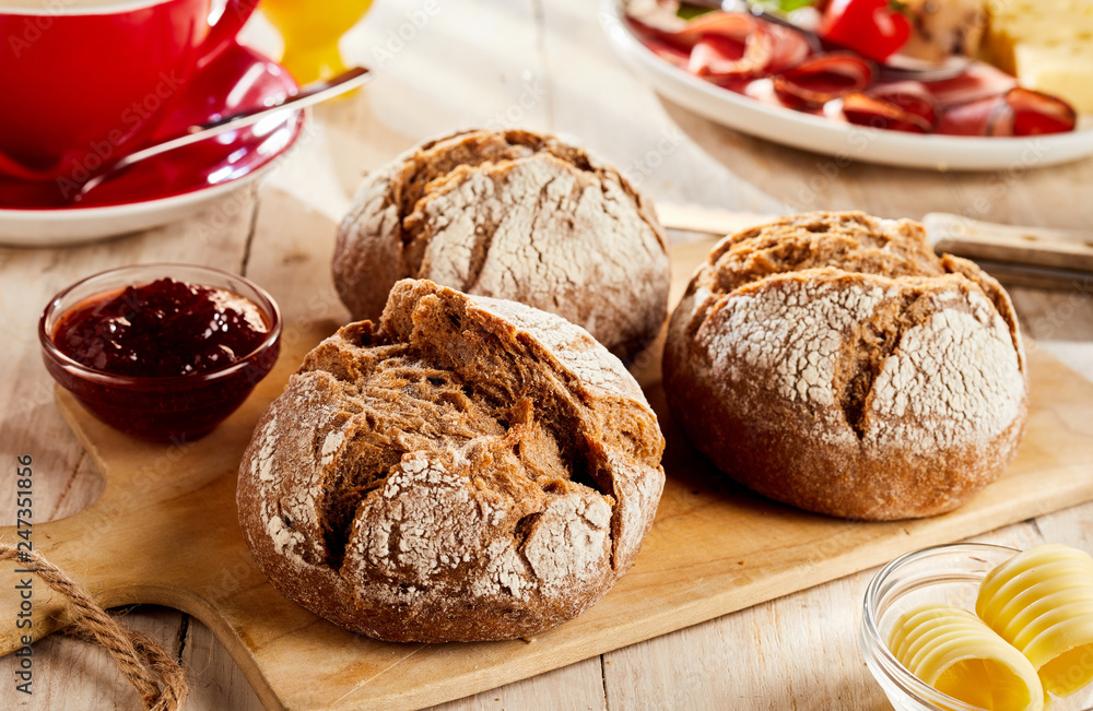 Naklejka premium Brown bread buns served on cutting board