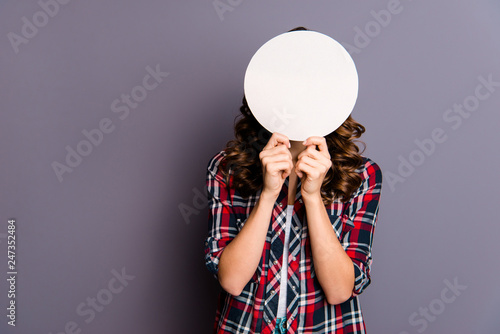 Close up portrait of unknown beautiful amazing she her lady arm show hold round card hide facial expression behind try guess my emotions wear casual checkered plaid shirt isolated grey background