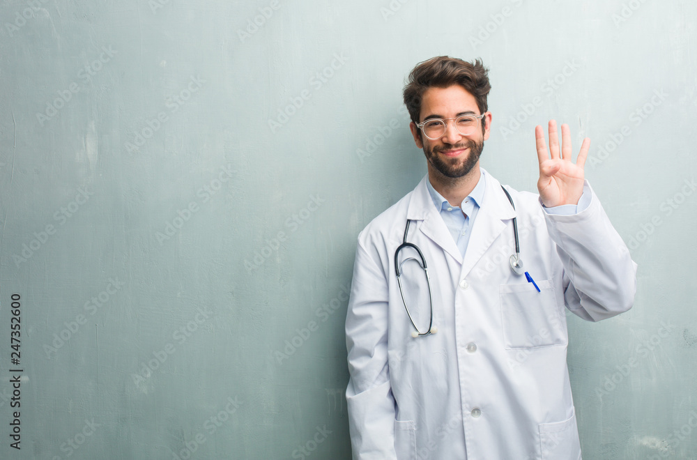 Young friendly doctor man against a grunge wall with a copy space showing the number four, symbol of counting, concept of mathematics, confident and cheerful Young friendly doctor man against a grunge wall with a copy space showing the number four, symbol of counting, concept of mathematics, confident and cheerful