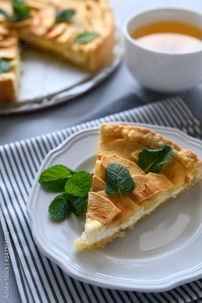 Homemade apple pie with cheese decorated mint leaves on gray wooden background. Teatime or vegetarian food concept. Selective focus.