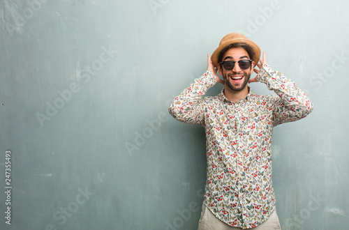 Young traveler man wearing a colorful shirt surprised and shocked, looking with wide eyes, excited by an offer or by a new job, win concept