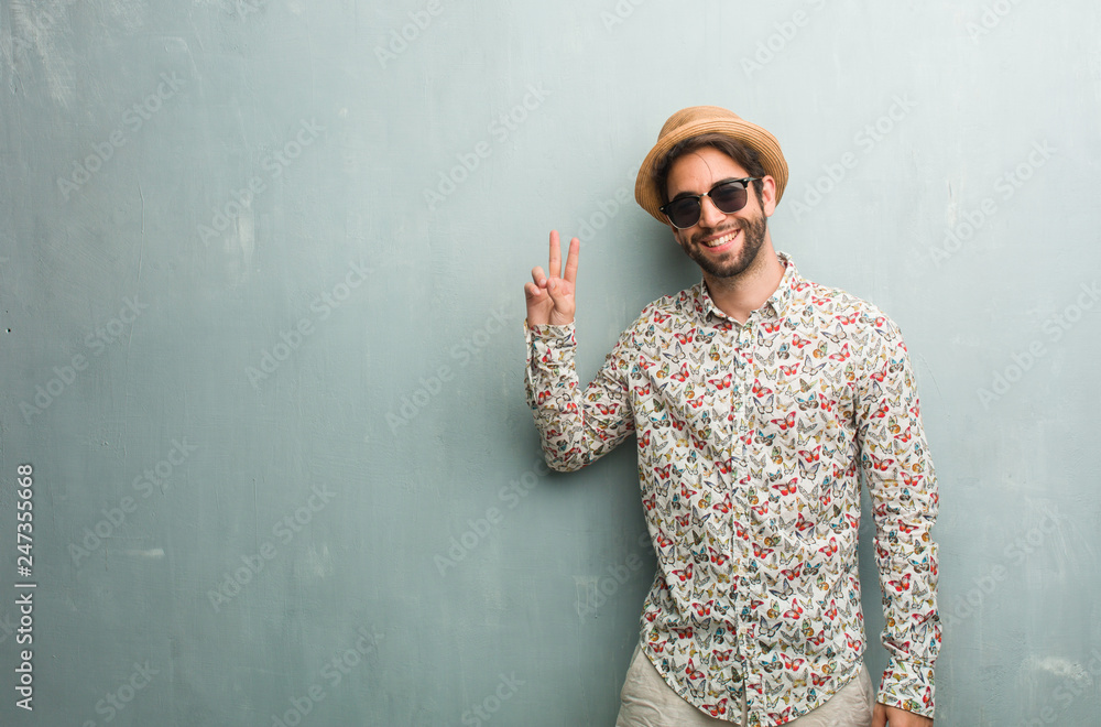 Young traveler man wearing a colorful shirt fun and happy, positive and natural, doing a gesture of victory, peace concept Young traveler man wearing a colorful shirt fun and happy, positive and natural, doing a gesture of victory, peace concept