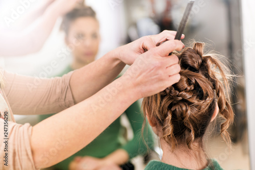 Hairstylist working on womans hairdo in close-up