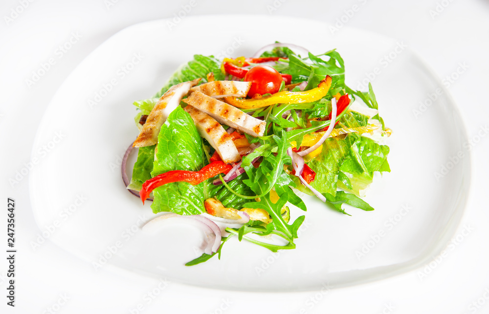 Delicious salad with meat, tomatoes and greenery on white Delicious salad with meat, tomatoes and greenery on white