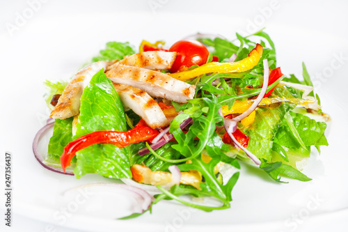 Delicious salad with meat, tomatoes and greenery on white