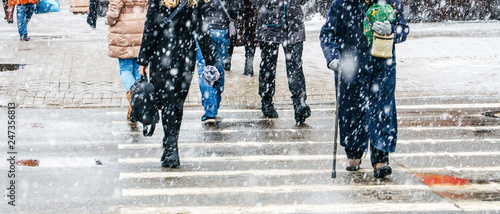 Winter City Slippery Sidewalk. Back view on the feet of people walking along the icy snowy pavement. Pair of shoe on icy road in winter. Abstract empty blank winter weather background