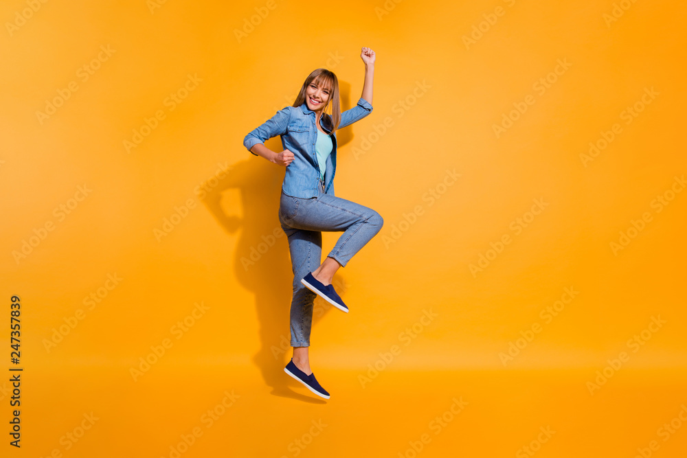 Full length body size photo jumping flight high amazing beautiful she her lady have walk hands arms legs in raised up glad wearing casual jeans denim shirt clothes isolated on yellow background
