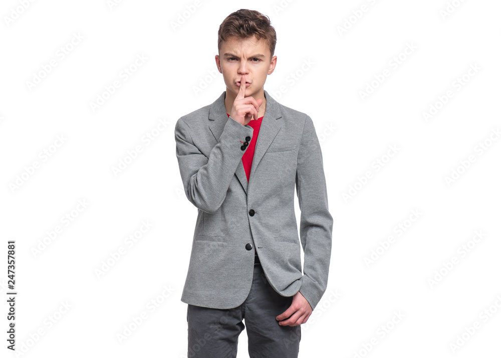 Handsome Teen Boy in suit making Silence gesture - Shh! Portrait of caucasian confident Teenager with finger on his lips isolated on white background. Serious child looking at camera. Handsome Teen Boy in suit making Silence gesture - Shh! Portrait of caucasian confident Teenager with finger on his lips isolated on white background. Serious child looking at camera.