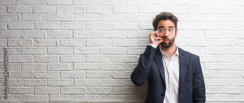 Schilderij op canvas Young friendly business man keeping a secret or asking for silence, serious face