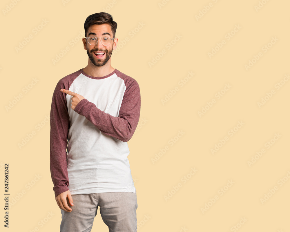 Young handsome man smiling and pointing to the side Young handsome man smiling and pointing to the side