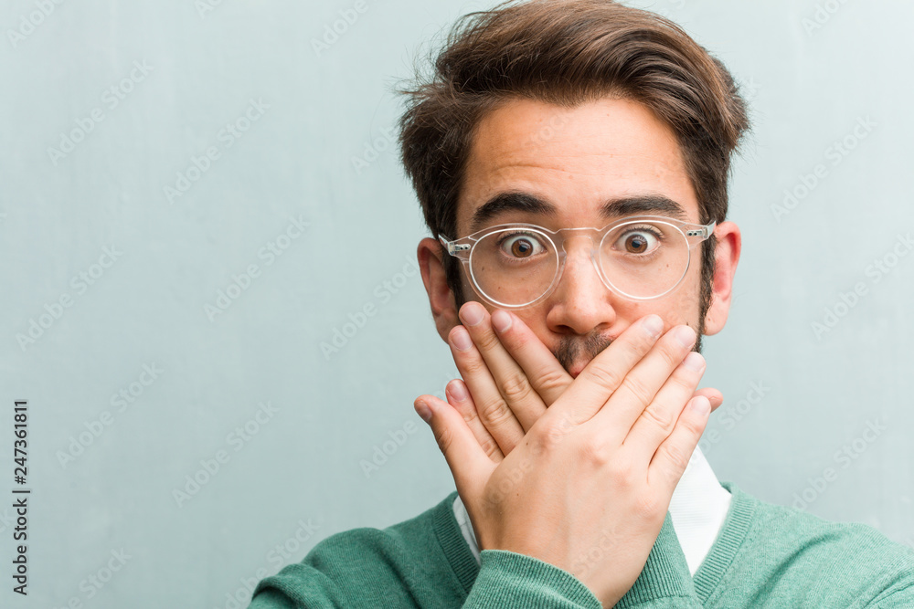 Young handsome entrepreneur man face closeup covering mouth, symbol of silence and repression, trying not to say anything Young handsome entrepreneur man face closeup covering mouth, symbol of silence and repression, trying not to say anything
